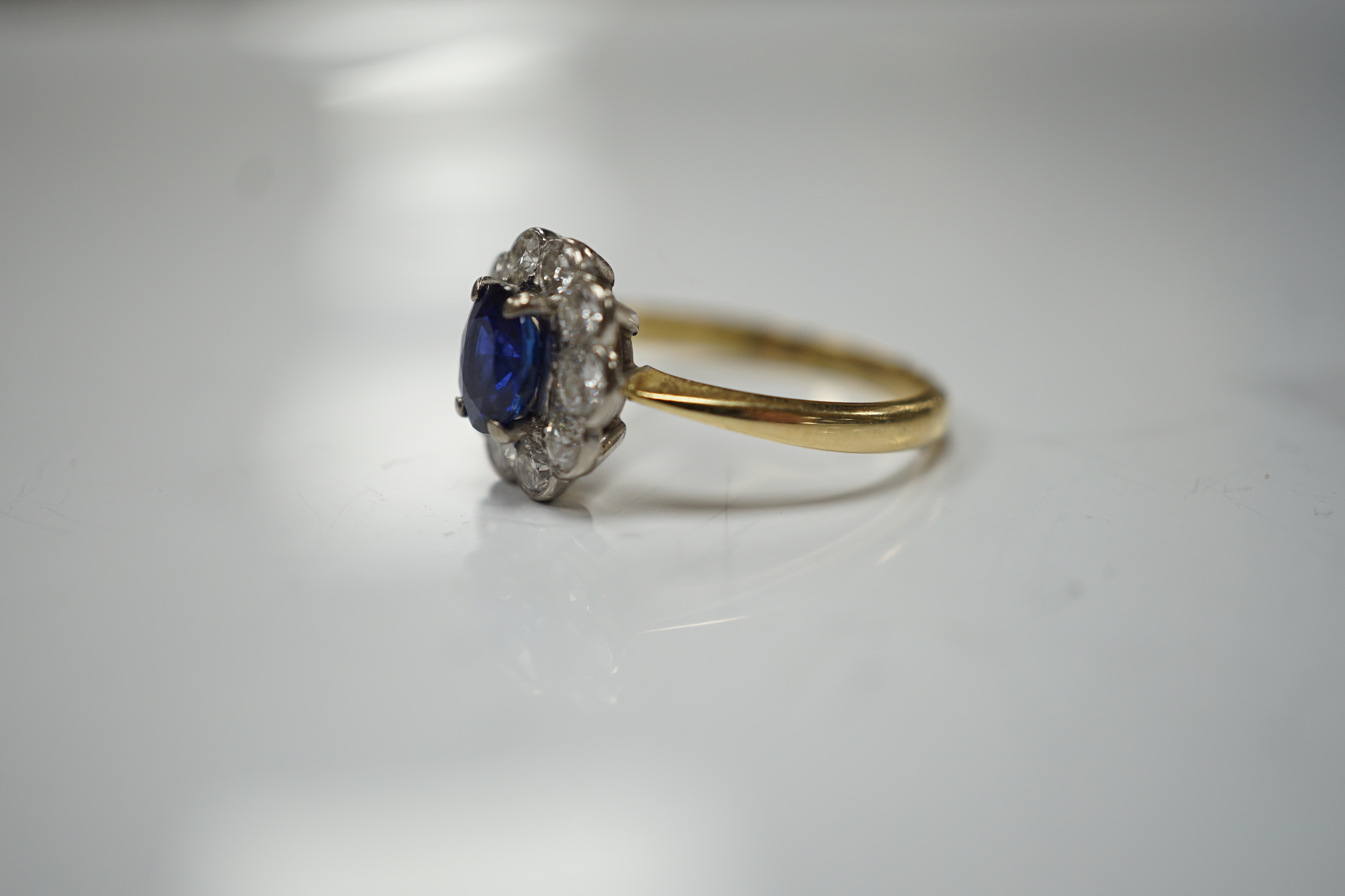 A modern 18ct gold, sapphire and diamond set circular cluster ring, size P/Q, gross weight 3.4 grams.